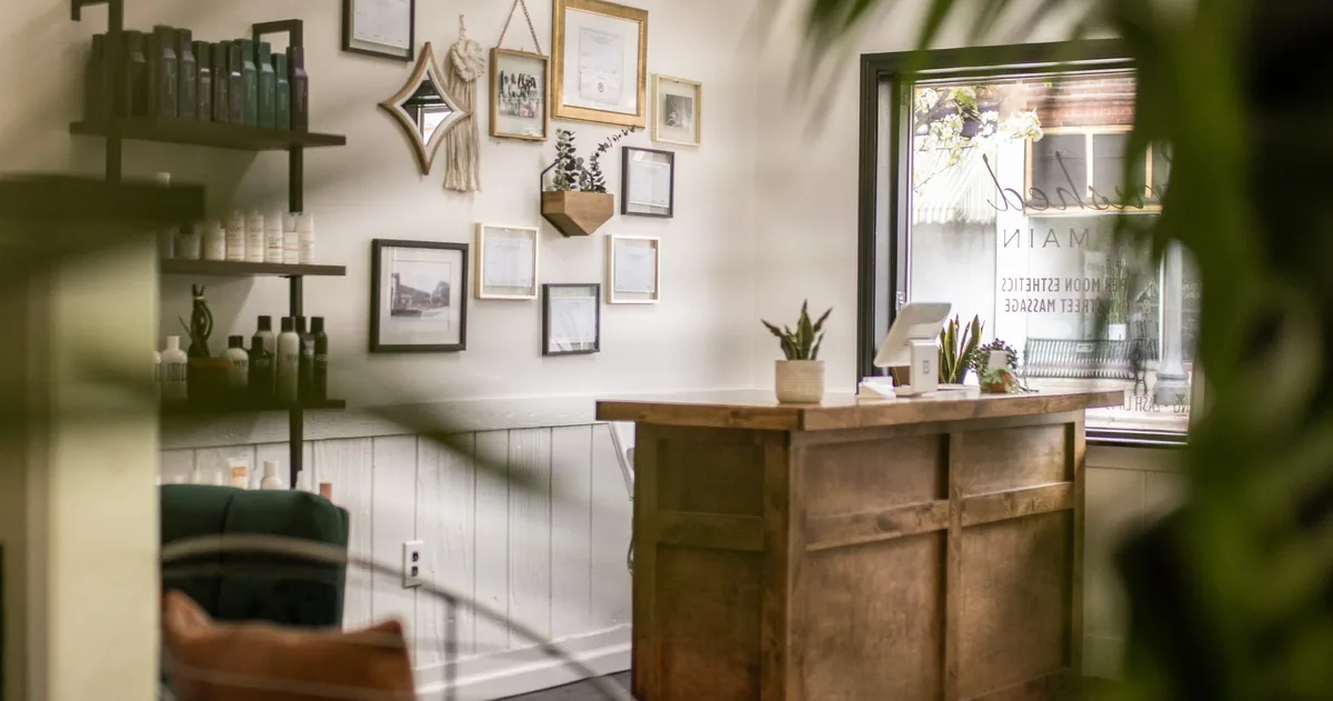 Brushed On Main front desk — warm wood reception with plants and certifications