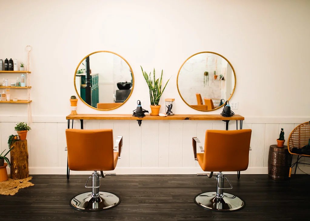 Inside Brushed On Main — styling stations with round mirrors and terracotta chairs