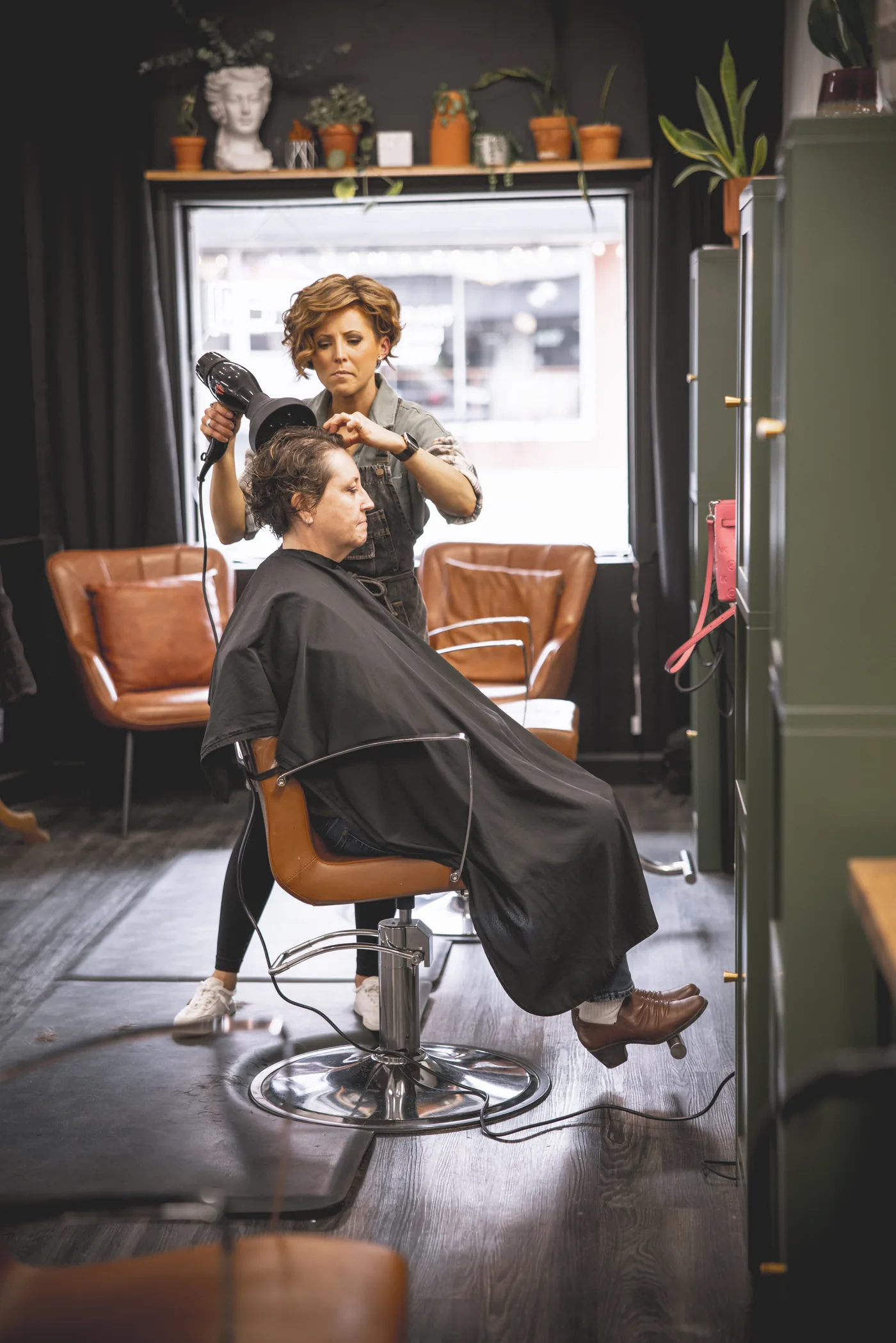 A Brushed On Main stylist blow-drying and styling a client's hair